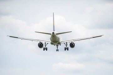 Airplane approaches landing over a cloudy sky in daylight at the airport. 