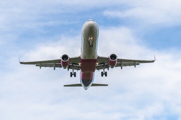 Airplane soaring through the cloudy sky above a busy airport during a clear afternoon
