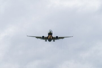 Airplane approaches runway under cloudy skies at an airport during daytime