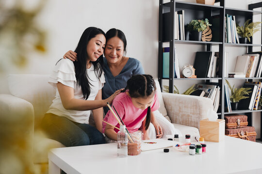 Joyful LGBTQ couple nurturing their child's creativity during an art activity at home in the afternoon