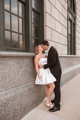 Obraz premium Engaged couple shares a kiss against a downtown Detroit building