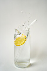Lemon water splash in glass with eco-friendly straw on white bac