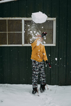 Child throwing giant snow ball on winter day