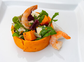 Colorful shrimp salad with fresh vegetables and dressing on a white plate