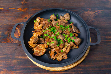 Savory roasted meat with green onions on rustic wooden table Savory vegetable pie served with fresh garnishes on a white plate