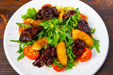 Colorful salad with fresh greens, tomatoes, and sweet fruit Savory vegetable pie served with fresh garnishes on a white plate