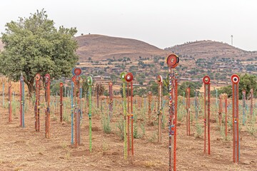 Fototapeta premium Colorful beaded poles in rural African landscape; community art installation