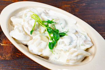 Delicious dumplings in creamy sauce served on wooden table Savory vegetable pie served with fresh garnishes on a white plate