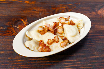 Savory dumplings topped with crispy bacon on a wooden table Savory vegetable pie served with fresh garnishes on a white plate