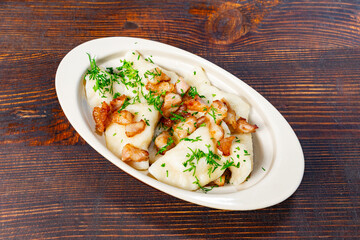 Dumplings topped with shrimp and herbs served on a wooden table Savory vegetable pie served with fresh garnishes on a white plate