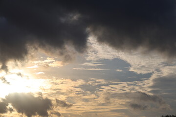 Dark gray rainy clouds on front view and blue sky with white clouds on background