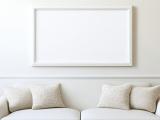 minimalist living room featuring blank white frame on wall above light colored sofa with decorative pillows, creating serene and elegant atmosphere