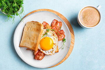 Breakfast sandwich  with fried egg, bacon and sprouts
