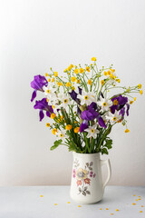 Home interior with a bouquet of spring flowers, irises and yellow ranunculus with white daffodils