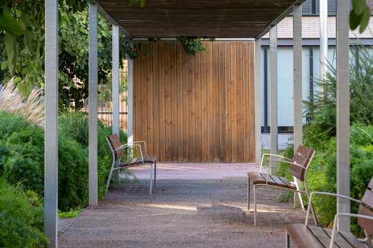 A peaceful park pathway flanked by lush greenery invites relaxation, with wooden seating providing a comfortable spot to enjoy nature's soothing ambiance in Barcelona Spain