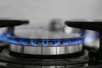 Gas burner of modern stove with burning blue flame, closeup