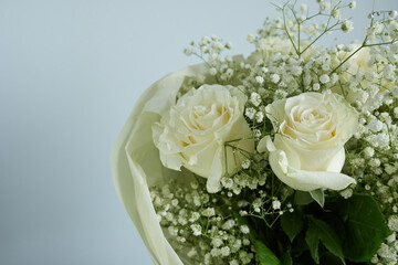 Bouquet of white roses and gypsophila on blue background