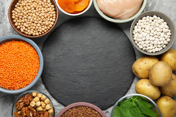 Diet plan for anemia. Different products rich in iron and slate board on grey table, flat lay. Space for text