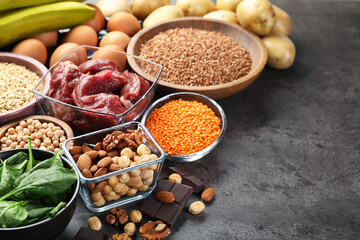 Diet plan for anemia. Different products rich in iron on grey table, space for text