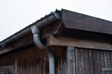 Close up of rain gutter pipeline on the roof of a wooden old house 