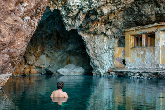 Backview of a man swimming at Kaiafas thermal baths inside a cav