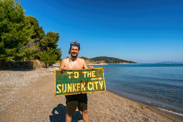 Man with scuba diving equipment holding a plate To the Sunken city