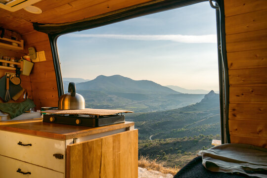 Inside view of a camper van kitchen with doors open to a mountain view