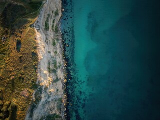 Drone aerial top view of a cliff landscape with sea blue water