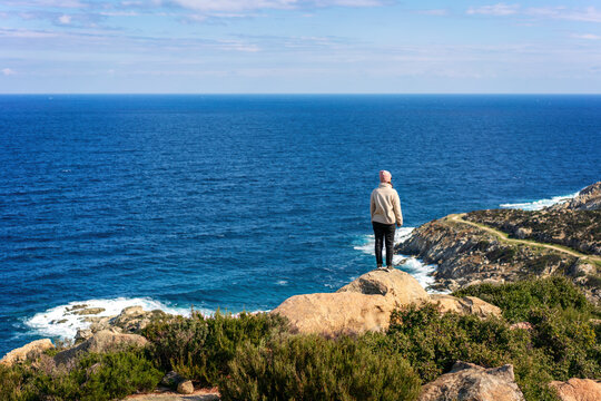 Back view of woman looking at the greek coast cliff landscape