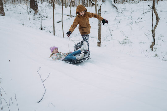 Laughing kids going downhill on sled on snow day