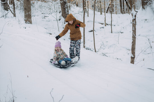 Children sledding down snowy hill on sled