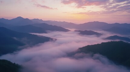 Fototapeta premium A breathtaking view of mountains enveloped in mist during a tranquil sunset.
