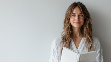 Obraz premium Pristine White Book with Blank Pages Held by a Smiling Woman