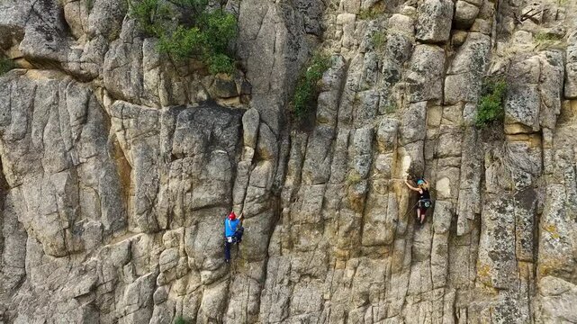 Imagen a&eacute;rea de un hombre y una mujer escalando por una pared de roca