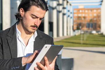 Business Professional With Tablet Outdoors Near Office Buildings. Successful Male Entrepreneur Communicating For Career Growth, Symbol Of Networking, Ambition, And Confidence.