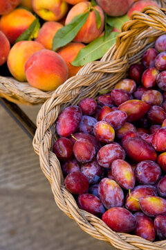 A vibrant market display showcasing fresh peaches and plums beautifully arranged in woven baskets, illustrating the abundance and bounty of seasonal fruits.