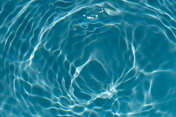 Blue water with ripples on the surface. Defocus blurred transparent blue colored clear calm water surface texture with splashes and bubbles. Water waves with shining pattern texture background.