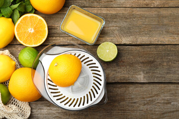 Plastic juicer, fresh oranges and limes on wooden table, flat lay. Space for text