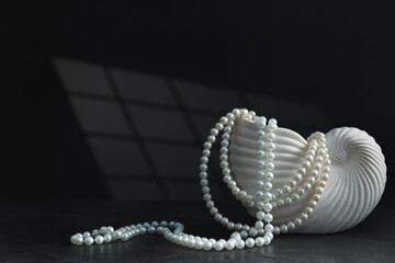 Stylish vase and elegant pearl jewelry on black background, space for text