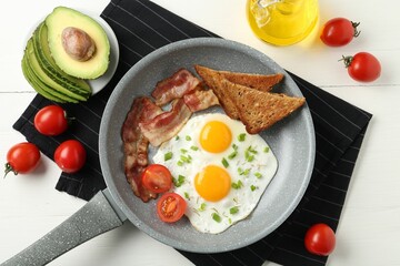 Tasty fried eggs with bacon and toasts served on white wooden table, flat lay