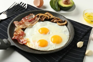 Tasty fried eggs with bacon and mushrooms served on white table, closeup