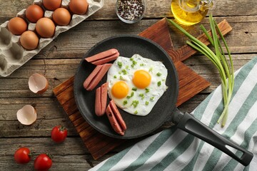 Tasty fried eggs with cut sausages served on wooden table, flat lay
