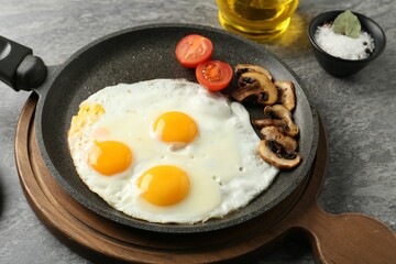 Tasty fried eggs with mushrooms served on grey table, closeup
