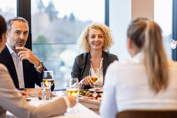 Portrait of businesswoman sitting with coworkers in restaurant during business lunch.