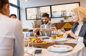 Portrait of businessman sitting with coworkers in restaurant during business lunch.