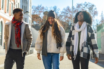 Happy multi ethnic students walking together on campus during winter break