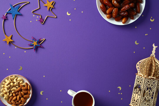 Ramadan flat lay composition. Top view crescent moon, decorative lantern, nuts, dates, and cup of tea on purple background. Ramadan Kareem and Eid Mubarak concept.