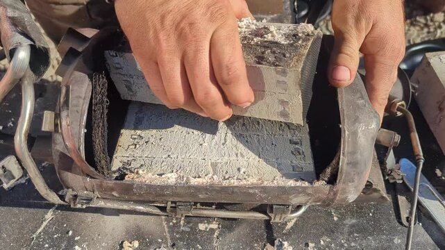 A car's catalytic converter covered in soot and clogged cells is being removed from the muffler. Environmental standards for reducing vehicle emissions