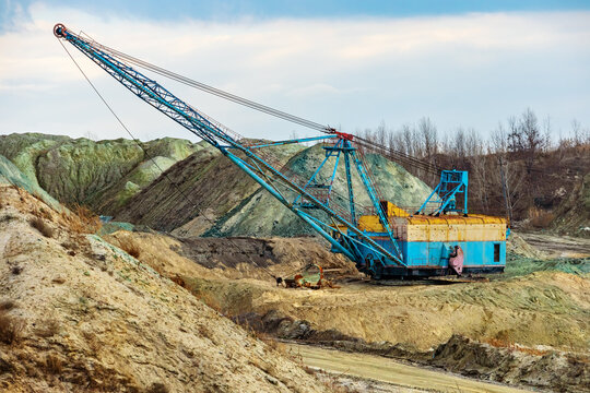 A dragline excavator walking in a mining quarry. Piles of soil and minerals