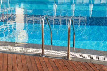 Obraz premium Grab bars ladder in the blue swimming pool
